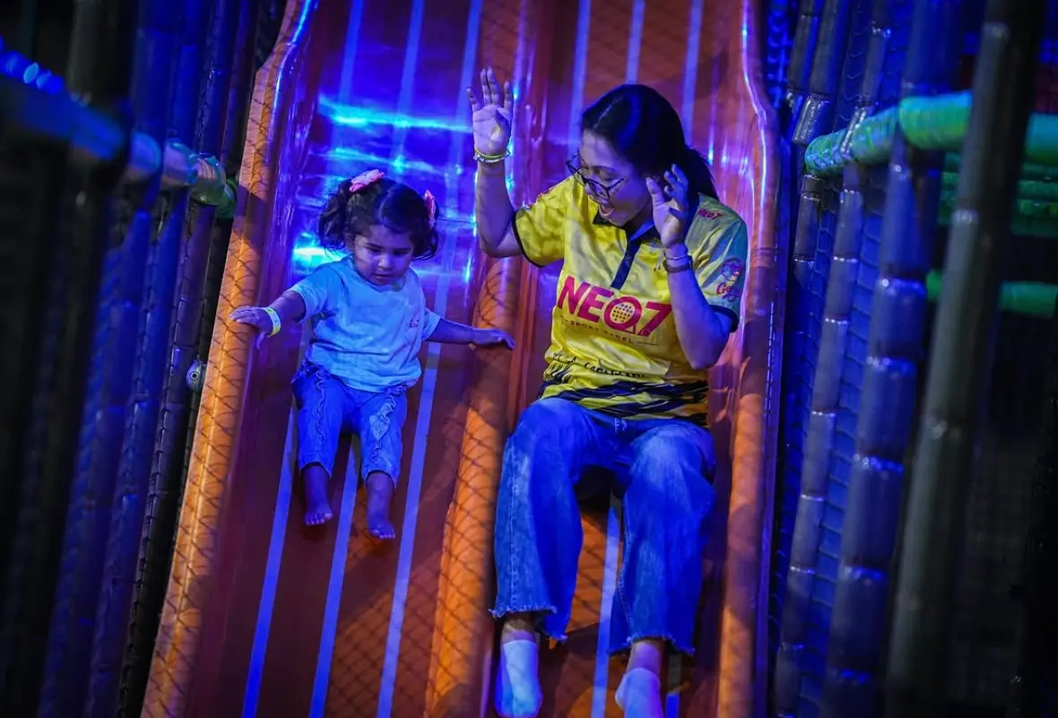 Una mamá y su hija bajando juntas por el tobogán